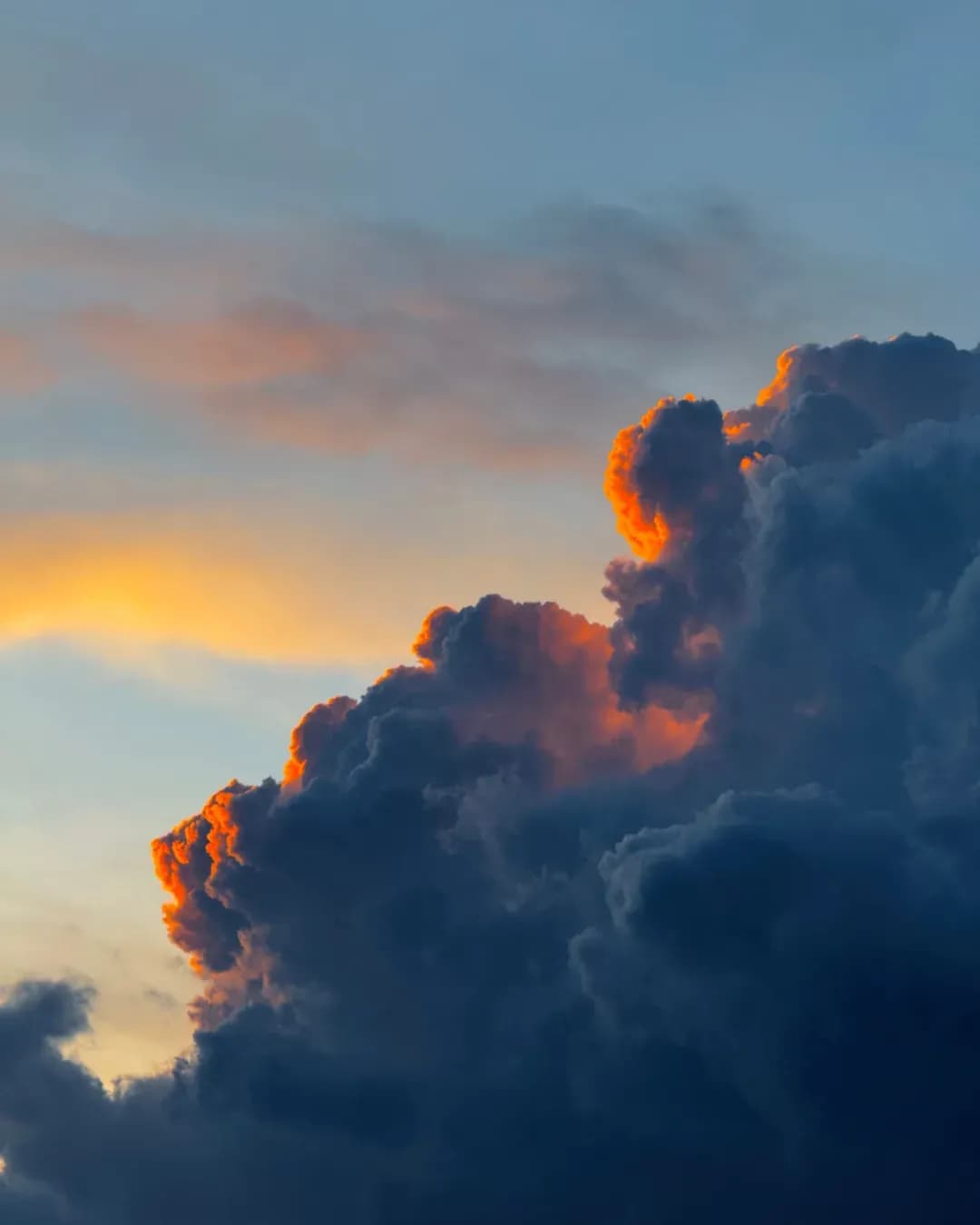Gros nuage d’orage dont les contours s’embrasent dans la lumière orangée du couchant